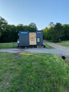 a tiny house sitting on the side of a gravel road at The Arkansas Tiny House in Mulberry