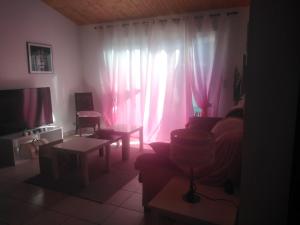 a living room with a couch and a window with pink curtains at bonheur in Médis