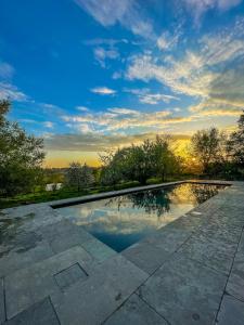 une piscine avec vue sur le coucher du soleil en arrière-plan dans l'établissement Holiday Home Les Plachettes, à Flobecq