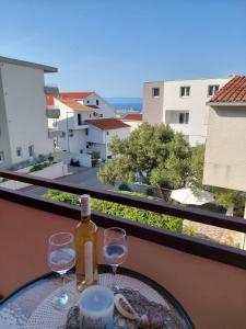 a table with two glasses and a bottle of wine on a balcony at Apartment Adriana in Makarska