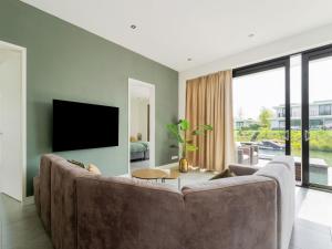 a living room with a large couch and a tv at Swanky villa in Zeewolde with garden in Zeewolde