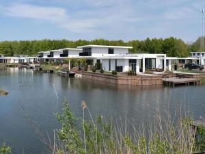 une maison sur l'eau avec un lac dans l'établissement Swanky villa in Zeewolde with garden, à Zeewolde