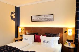 um quarto de hotel com uma cama com almofadas brancas e vermelhas em Hotel Blauer Bock em Munique