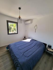 a bedroom with a bed with a blue comforter and a window at Villa Célestine in Calvi