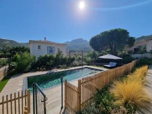 a swimming pool in a backyard with a wooden fence at Villa Célestine in Calvi