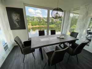 a dining room with a table and chairs and a large window at Apartments Saaldorf-Ferienhaus mit 6 Apartments 45qm-120qm direkt am Thüringer Meer-Bleilochtalsperre in Bad Lobenstein