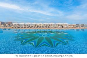 a swimming pool with chairs and umbrellas on a beach at Taj Exotica Resort & Spa, The Palm, Dubai in Dubai