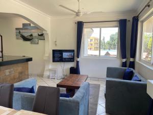 a living room with couches and a table and a tv at Royal Palms Apartment A4 in Mombasa