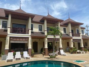 a large house with a swimming pool in front of it at Organgrinder Thai Paradise South in Cha Am