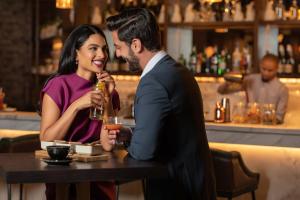 a man and woman sitting at a table in a bar at Taj Exotica Resort & Spa, The Palm, Dubai in Dubai