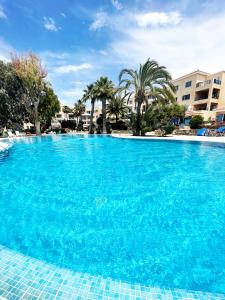 a large blue swimming pool with palm trees and buildings at Direct Sea View & Quality Bed - Kings Palace 1 bed in Paphos City