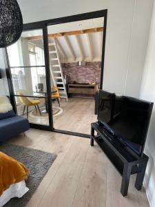 a living room with a tv and a mirror at Gezellige knusse studio met bubbelbad in Huizen