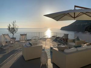 un patio con sedie, ombrellone e oceano di 'A Alera Room & Breakfast a Malfa