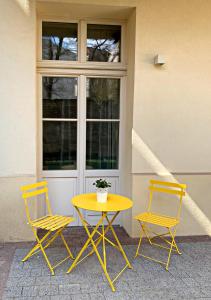 Old Town Suite في كراكوف: كرسيين وطاولة وكراسي صفراء امام المبنى