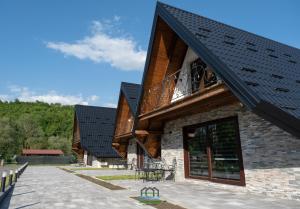 a house with a black roof and a patio at Holiday Houses Green Queen in Bihać