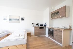 eine Küche mit Holzschränken und ein Sofa im Zimmer in der Unterkunft T&K Apartments - Studio Apartments - 22 min MESSE DUS & Airport DUS in Krefeld