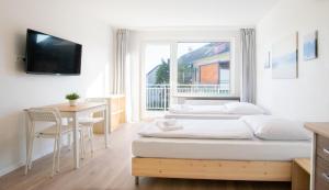 a bedroom with two beds and a table and a window at T&K Apartments - Studio Apartments - 22 min MESSE DUS & Airport DUS in Krefeld