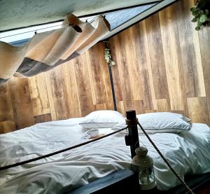 a bed in a room with a wooden wall at Tripsylvania Tiny House Fili in Şirnea