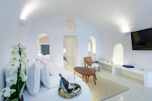 a white living room with a white couch and a table at Aristos Life Luxury Cave Villas in Oia +37 photos