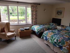 1 dormitorio con 2 camas, silla y ventana en The Old Sun private cottage, en Frome