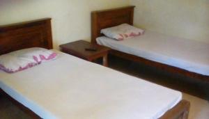 um quarto com duas camas e uma mesa de cabeceira em Leaf Guest House em Gampola