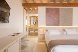a bedroom with a bed and a desk with a tv at Fontsanta Hotel Thermal & Spa - Adults Only in Colònia de Sant Jordi
