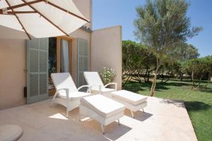 a patio with white chairs and an umbrella at Fontsanta Hotel Thermal & Spa - Adults Only in Colònia de Sant Jordi