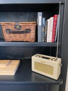 ein Regal mit einem Radio, einem Korb und Büchern in der Unterkunft The Old Shop, A Two Bed Flat in Inverkip Village in Inverkip