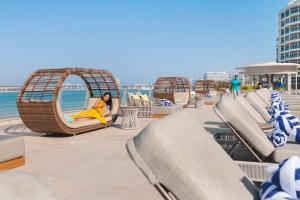 a woman sitting on a swing on the beach at Taj Exotica Resort & Spa, The Palm, Dubai in Dubai