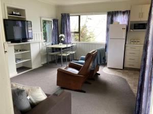 a living room with a couch and a refrigerator at Kiwi beach bach in Riverton