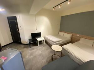 a room with two beds and a desk with a computer at Fengjia Gift Box Homestay in Taichung
