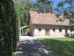 uma casa de pedra com uma porta amarela e um quintal em Takács vendégház em Orfű