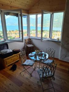 Una mesa y sillas en una habitación con ventanas. en La casa della Cindy, en Dervio