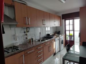cocina con armarios de madera, fregadero y lavavajillas en Faro Stadium Flat by Freetimealgarve, en Faro