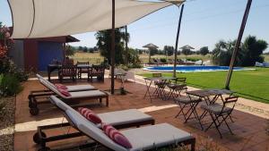 un patio con sillas, mesas y una sombrilla en Quinta dos doze Sobreiros - Quarto Sol, en Ferreira do Alentejo