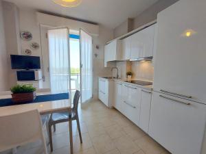 una cocina con armarios blancos y una mesa con comedor. en Montebianco 30 en Lido di Pomposa