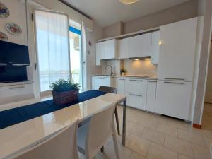 una cocina con armarios blancos y una mesa con una planta. en Montebianco 30 en Lido di Pomposa