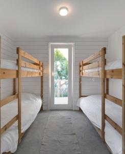 two bunk beds in a room with a window at Precious Cabin in Comporta in Comporta