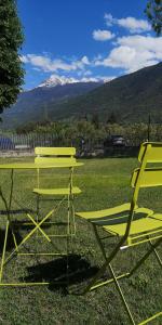 twee gele picknicktafels en stoelen in een veld bij Lovely 1bedroom apartment central valley location in Aosta