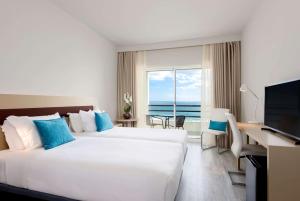 um quarto de hotel com duas camas e uma secretária e uma janela em TRYP by Wyndham Lisboa Caparica Mar em Costa da Caparica