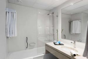 a bathroom with a shower, sink, and mirror at TRYP by Wyndham Lisboa Caparica Mar in Costa da Caparica
