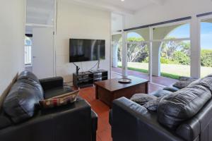 a living room with two leather couches and a flat screen tv at Cordova - Perfect Summer or Winter Getaway in Merimbula