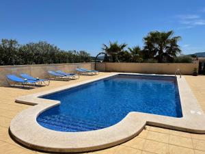 a swimming pool with lounge chairs next to a wall at Grapevine Manor in Monóvar