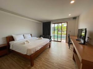a bedroom with a bed with a television and a desk at Utopia Resort in Lamai