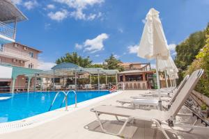 a pool with lounge chairs and an umbrella at BEL AIR HOTEL in Nydri