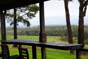 een veranda met een tafel en stoelen en uitzicht op een veld bij Gorgeous villa 10 acre of land in Menzies Creek
