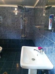 baño con lavabo blanco y azulejos azules en Guest House-Waterfall en Chokhuldi