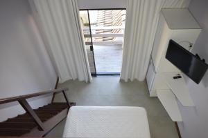 un salon avec une chaise blanche et une télévision dans l'établissement Pousada Sweet Home, à Búzios