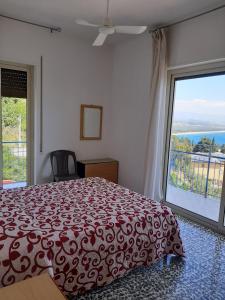 a bedroom with a red bed and a large window at Hotel Conca d'Oro in Stalettì