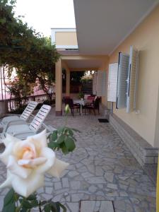 eine Terrasse mit einer weißen Rose sowie einem Tisch und Stühlen in der Unterkunft Apartments Villa Jagoda in Rab